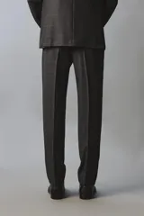 Pantalón de traje de corte regular fit confeccionado en lana de origen italiano. Presenta un diseño de cuadros sutiles, bolsillos laterales, bolsillos traseros de doble vivo con botón y cierre frontal con cremallera y botón.