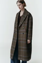 Abrigo largo de corte oversize con estampado de cuadros en tonos marrones y líneas azules. Presenta cuello de solapa, cierre frontal cruzado con botones, mangas largas y bolsillos delanteros con solapa.