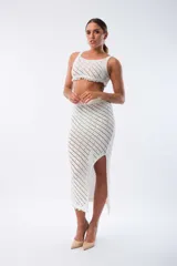 Pollera midi de tejido calado color blanco, con cintura elástica y abertura lateral.