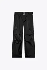 Pantalón cargo de tiro medio en color negro, confeccionado en tejido técnico con acabado satinado. Presenta corte recto y holgado, múltiples bolsillos laterales tipo cargo con solapa y un bolsillo adicional con cierre en la pierna derecha. Incluye un cinturón integrado con hebilla metálica y trabillas en la cintura.