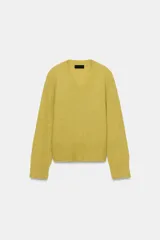 Jersey de punto con mezcla de lana y alpaca, color amarillo mostaza, con cuello en pico y manga larga. Presenta acabados en rib en puños y bajo.