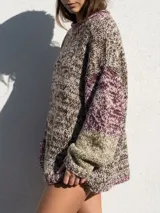 Sweater de tejido de punto grueso con diseño multicolor en tonos tierra, chocolate, bordeaux y beige. Presenta un corte amplio y relajado, con cuello redondo y mangas largas.