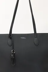 Cartera tipo tote de diseño minimalista y estructura flexible, confeccionada en material sintético con acabado mate. Cuenta con asas largas para llevar al hombro y un compartimento principal amplio.