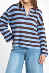 Sweater de punto con diseño de rayas horizontales en color marrón y celeste, corte oversize, cuello polo con cierre frontal y mangas largas.