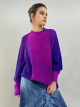 Buzo tejido de lana merino con diseño oversize, manga ranglan y cuello levemente elevado. Presenta un degradado de color vibrante en tonos violeta y fucsia.