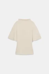 Top fluido de color beige con cuello perkins y mangas acampanadas por debajo del codo. Presenta un diseño de bajo redondeado y textura sutil en la tela.