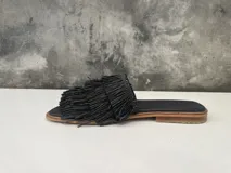 Sandalia baja de cuero negro con flecos de rafia en la capellada.