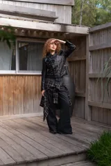 Campera de eco cuero negro con solapas anchas, cierre diagonal metálico y detalle de múltiples ojalillos metálicos distribuidos en el frente y las mangas.