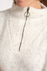 Sweater de tejido de punto color blanco roto, con motas de colores (efecto tweed o confetti), cuello alto con cierre metálico parcial y calce oversize.