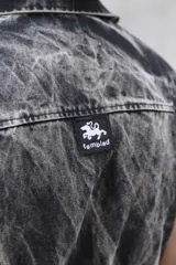 Mono de jean con lavado gris efecto desgastado, con múltiples cortes estructurales, cierre frontal oculto por cartera, cintura elástica y bordado de logo en azul. Incluye un pequeño accesorio de bolso desmontable para la cintura.