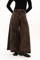 Pantalón de jean de tiro alto con corte wide leg y diseño de paneles verticales. Presenta un acabado lavado con efecto desgastado en tono chocolate, bolsillos funcionales y cierre frontal con botón metálico.