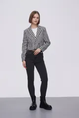 Blazer corto de poliéster con diseño a cuadros en blanco y negro, cuello solapa y cierre frontal de doble botonadura.
