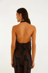 Top de escote halter con diseño cruzado, lazo lateral y estampado geométrico de ondas en tonos negro y marrón con líneas doradas.
