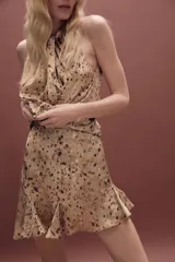 Falda mini de tiro medio con diseño asimétrico y bajo acabado en volantes. Presenta un estampado de manchas en tonos tierra y cierre lateral con cremallera oculta.