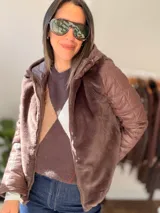 Campera con cuerpo de piel sintética tipo teddy y mangas acolchadas. Presenta cierre frontal, capucha y diseño de corte recto.