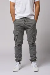 Pantalón cargo color beige de gabardina, con corte ajustado, bolsillos laterales con fuelle y puños elásticos en los tobillos.