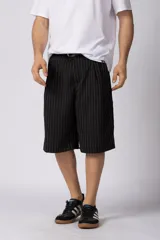 Bermuda sastrera baggy de color negro con diseño de rayas diplomáticas finas blancas. Cuenta con bolsillos laterales y presillas para cinturón.