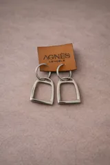 Aros colgantes plateados con dije en forma de estribo y argolla superior.