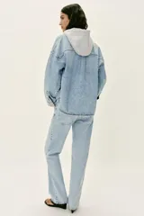Cazadora de denim oversize con capucha gris desmontable, cuello camisero, cierre frontal con botones metálicos y bolsillos delanteros de plastrón.