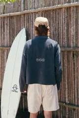 Buzo gris de tejido de punto con textura acanalada, cuello polo y escote en V. Presenta un estampado frontal con la inscripción 'glassy wa'.