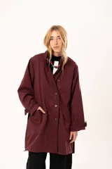 Trench de gabardina Tencel con silueta relajada, cierre frontal con botones, cuello amplio, bolsillos laterales y lazos regulables en los puños.