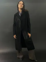 Tapado largo de paño de lana color negro con estampado abstracto brillante en el frente. Tiene cuello con solapas, bolsillos laterales y terminación al tallo vivo.