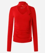Blusa entallada de microfibra color blanco, con escote en V, mangas largas y detalle de frunces en los laterales. Presenta un lazo integrado en el cuello que permite anudarlo, aportando un toque sofisticado al diseño.