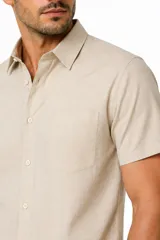 Camisa negra de manga corta, con cuello clásico, cierre frontal con botones y bolsillo ojal en el pecho.