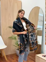 Bufanda larga con estampado de cuadros y flores en tonos marrón, azul y beige, con flecos en los extremos.