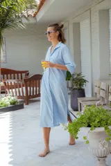 Vestido camisero celeste de corte midi, con cuello clásico, mangas 3/4 y cierre frontal con botones.