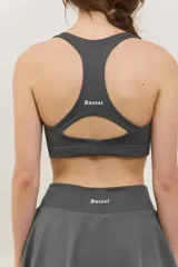 Top deportivo de sujeción media con escote redondo y espalda abierta. Presenta un diseño al cuerpo con elástico oculto en la cintura.