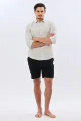 Short de baño cargo color negro, de diseño liso con bolsillos laterales y bolsillos utilitarios con solapa y botón en las piernas. Cuenta con cintura elástica ajustable mediante cordón.