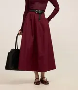Pollera evasé midi color borgoña, confeccionada en tricolina de algodón sostenible, con tiro alto, pliegues delanteros y cierre trasero por cremallera.