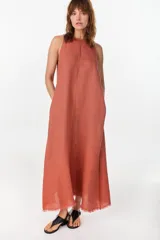 Vestido midi verde de lino italiano, con diseño sin mangas, cuello redondo y estampado de líneas onduladas punteadas. Cuenta con bolsillos laterales.