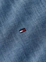 Camisa de chambray celeste de puro algodón, corte regular, con cuello abotonado, puños redondeados con dos botones y logo de Tommy Hilfiger bordado en el pecho.