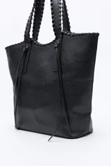 Cartera tipo tote de diseño amplio y textura símil cuero, con asas trenzadas y terminaciones artesanales.