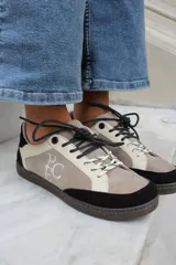 Championes de estilo urbano en combinación de tonos marrones y crema, confeccionados en gamuza y cuero. Presentan cordones jaspeados, suela de goma y detalle de logo bordado en el lateral.