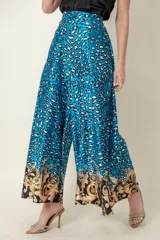 Pantalón palazzo de satén con estampado animal print en tonos celeste, negro y blanco. Tiene cintura elastizada y corte amplio.