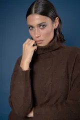 Buzo de cuello alto tejido en lana, con diseño de ochos en el centro y mangas largas con hombros caídos.