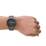 Reloj Armani Exchange modelo Hampton con caja y correa de acero color gris plomo, esfera negra con detalles en blanco y tres subesferas.
