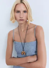 Vestido midi de corte recto con diseño estilo vaquero, confeccionado en una mezcla de algodón y lino. Presenta un escote cuadrado, tirantes finos ajustables y un detalle drapeado en uno de los laterales de la cintura. Cuenta con cierre de cremallera lateral.