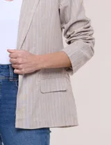 Blazer de lino y algodón color beige con diseño de rayas diplomáticas blancas, solapa clásica, cierre de un botón frontal y bolsillos laterales con solapa.