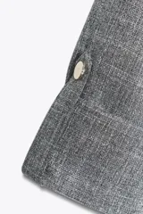 Chaqueta jaspeada color beige, con cuello solapa, manga tres cuartos con trabilla y botón, bolsillos delanteros de plastrón con solapa, bajo ajustable con cordones interiores y cierre frontal con botones a presión.