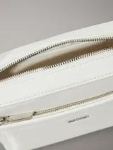Cartera tipo bandolera rectangular de color blanco, con bolsillo exterior frontal y cierre de cremallera. Presenta herrajes metálicos plateados y dos correas desmontables: una fina y ajustable, y otra ancha con logo bordado.
