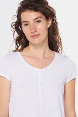 Remera color beige con cuello redondo, mangas cortas, bolsillo pequeño en el pecho y media botonadura frontal.