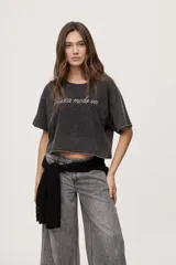 Remera gris de fit amplio, con mangas cortas y cuello redondo. Presenta efecto lavado y estampa frontal con aplicación de strass con la frase "fiesta mode on".