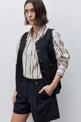 Short de tiro alto confeccionado en algodón, con calce relajado y silueta recta. Presenta pinzas delanteras, bolsillos laterales y botones decorativos en la cintura.