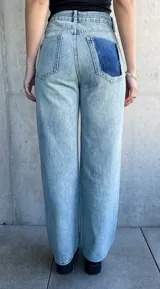 Pantalón de jean celeste con estampado de cuadrados plateados reflectantes.