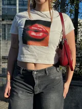 Remera negra corta con estampado frontal de labios rojos y la frase "Don't be jealous.", manga corta y cuello redondo.