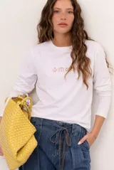 Remera blanca de manga larga con cuello redondo y diseño bordado en el pecho.